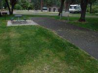 Recreational vehicle site at Mckay's Bend Campground. Grass, picnic bench in foreground.  RV and bathrooms in background.