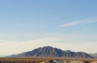 A small mountain range rises from a desert floor.