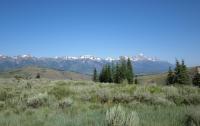 Landscape view of the Snake River land parcels with mountains and trees with a blue sky.