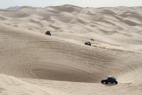 Off highway vehicles scamper over rolling sand dunes.