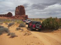OHV users follow a dirt path through a desert landscape