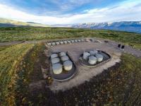 Oil and gas infrastructure including pipes, valves and tanks on a gravel pad 