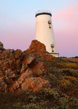 Light house with rocks in the foreground.