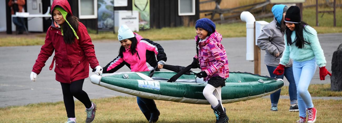 Fourth graders laugh while carrying a kayak at the South Fork of the Snake River in Idaho