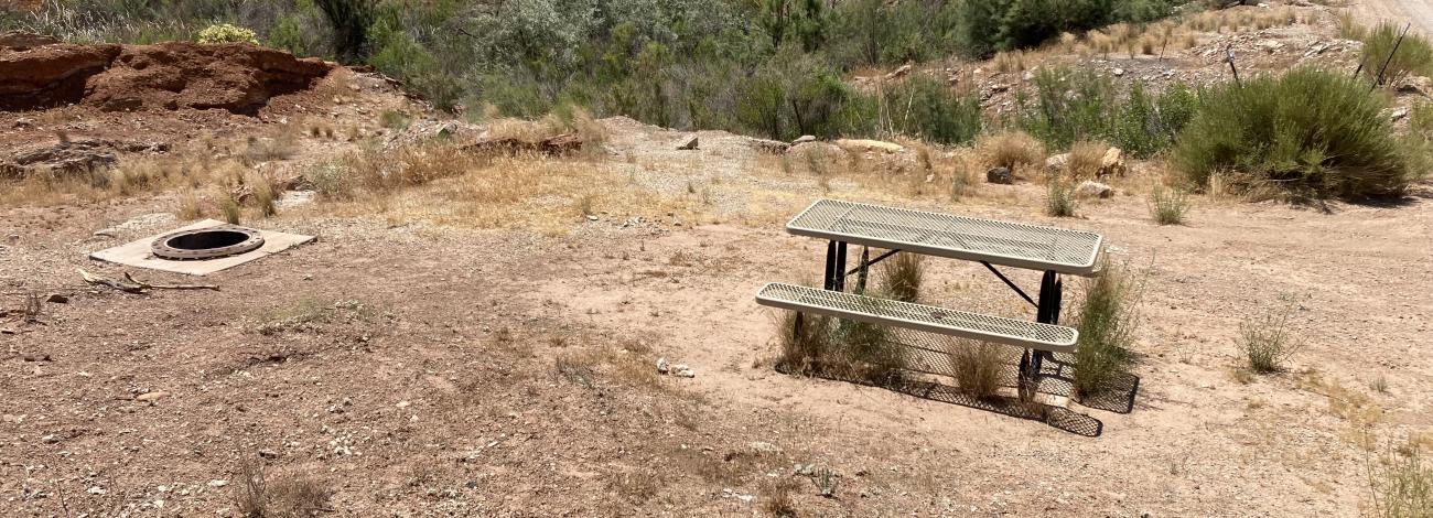 Flat, gravel campsite with a desert wash full at Quail Creek Reservoir Designated Dispersed Camping Area