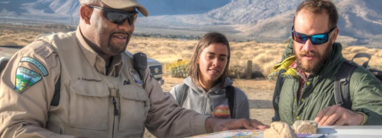 A law enforcement ranger helps two hikers