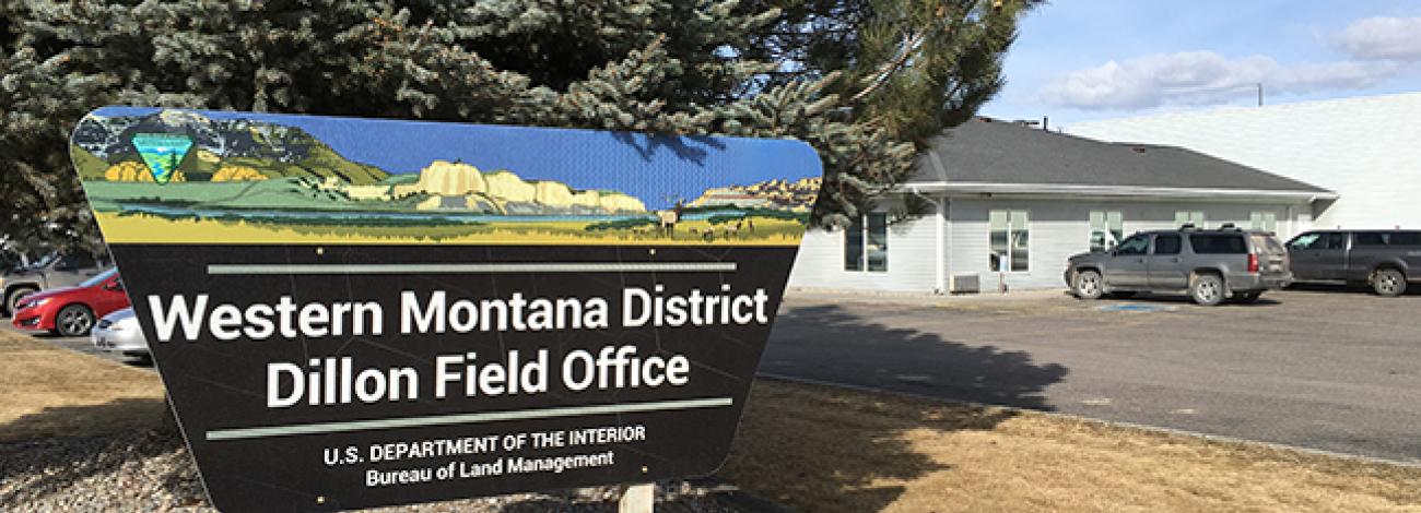 Dillon Field Office Sign. Large tree and office building in background.