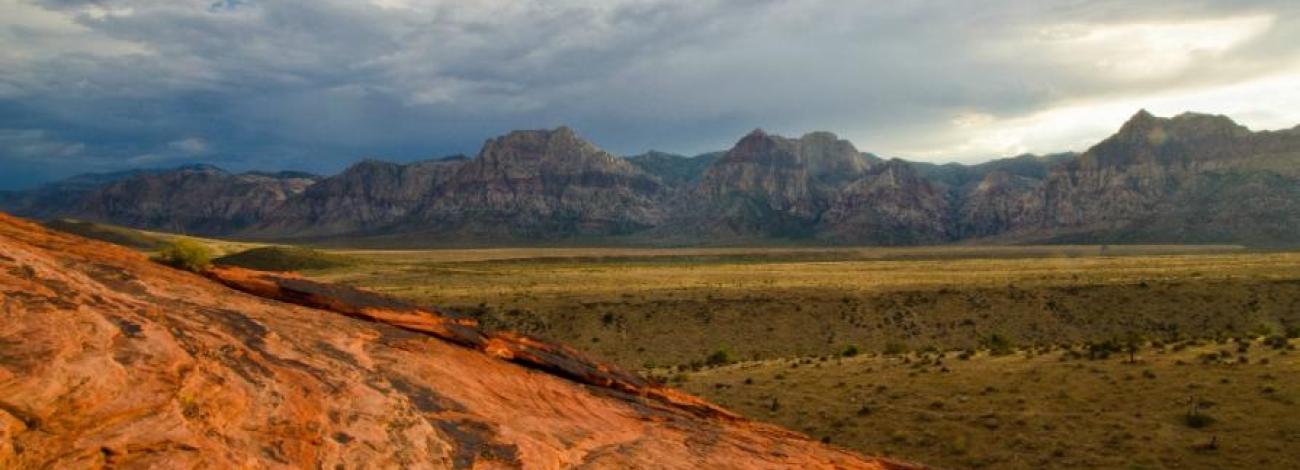 Image looking up from a hill top through the flats and multiple mountains ahead