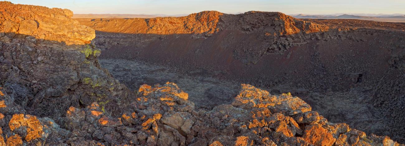 short flat rocky valley surrounded by reddish rocks being hit by sunlight. No vegetation.