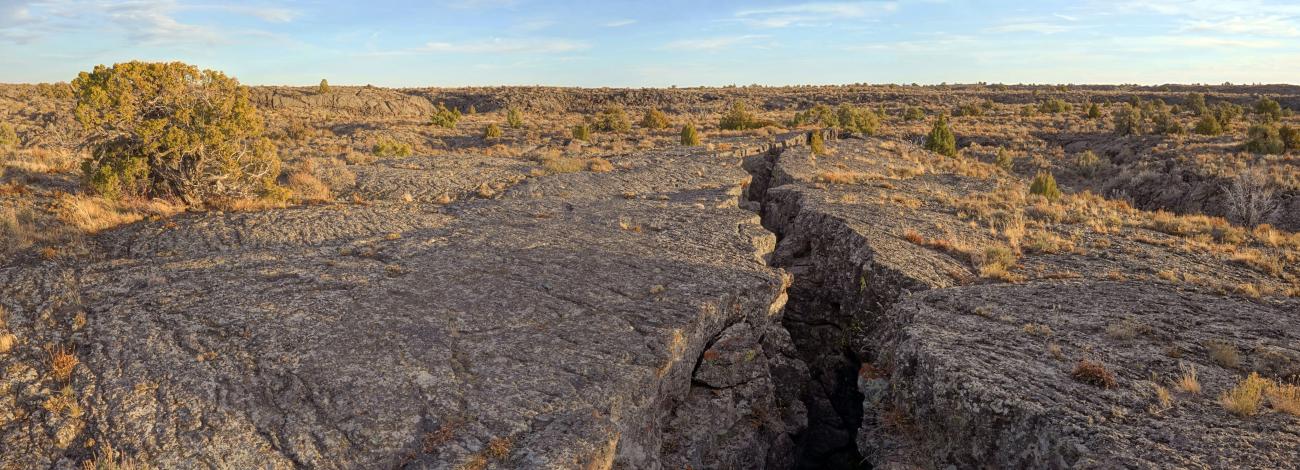 Flat rocky crevasse with shrubbery around on a clear sunny day