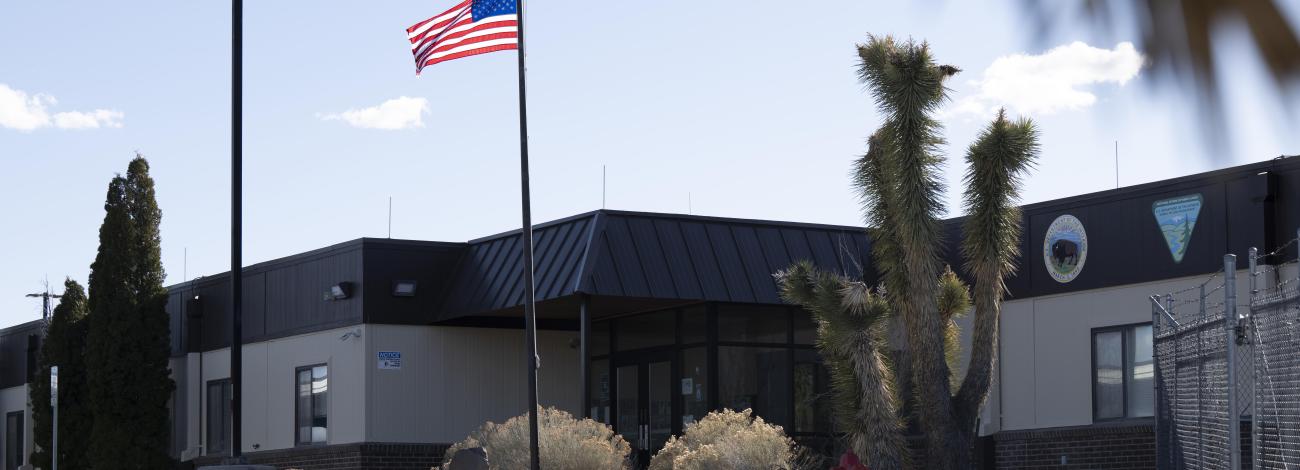 An American Flag waves above an office building with Department of Interior and Bureau of Land Management signs.