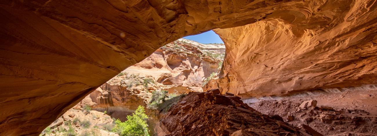 A small cave in a desert with a small stream flowing through.