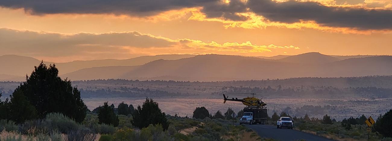 sunset view of mountain landscape with a helicopter in the distance