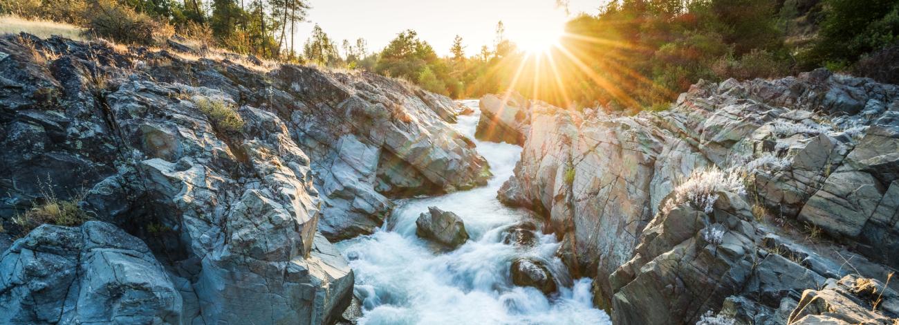 Sun sets over a cool stream rushing through a gorge