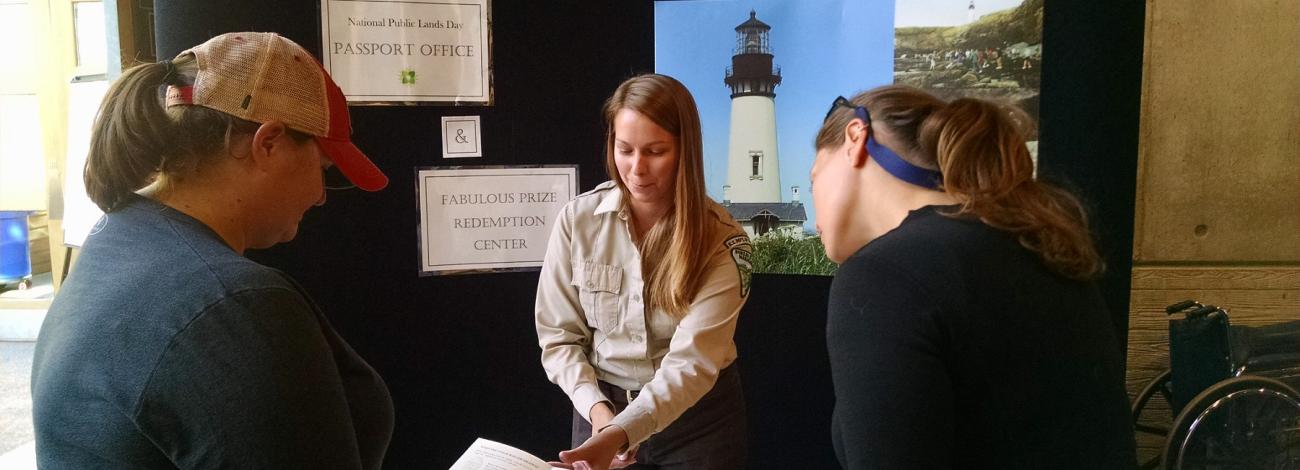 Group of people looking over a display table at which a park ranger stands