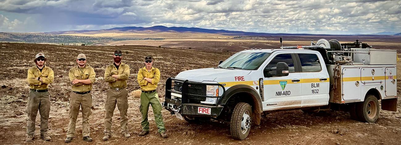 Four members of the Albuquerque District Fire Crew pose with a fire truck at the 2025 Buck Fire.