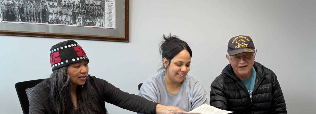 A group of people sit at a table with a laptop to discuss application process