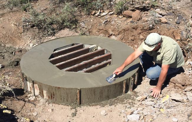 A cement worker smooths a cap on a mine