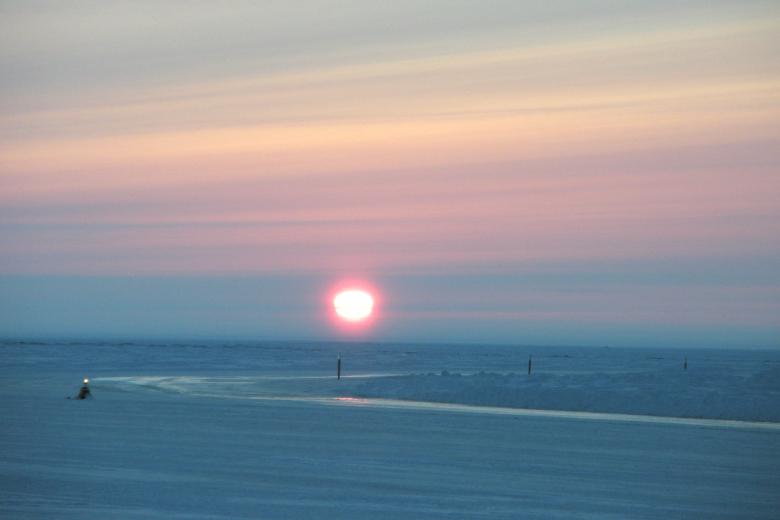 Ice road in northeast National Petroleum Reserve in Alaska with sun very low on the horizon.