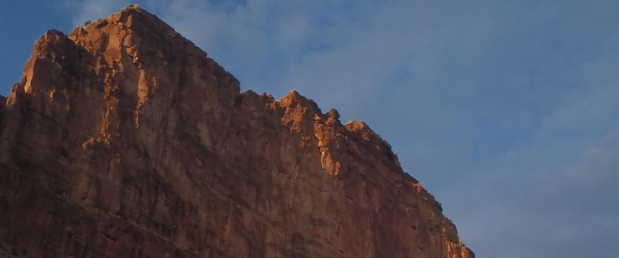 view of cliff from the ground extruding into the open sky