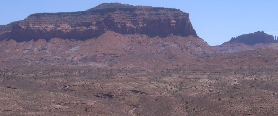 Vast empty landscape with mesa protruding into a clear blue sky 