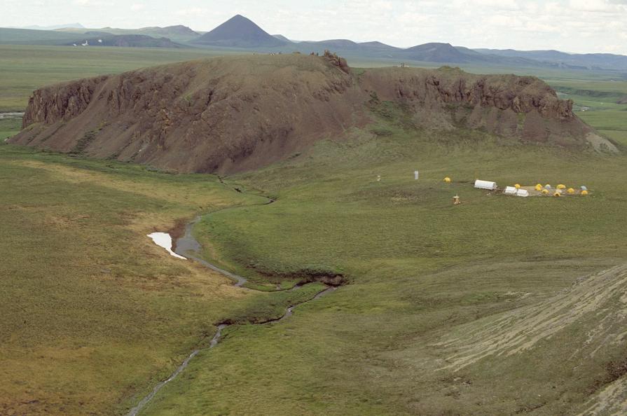 large hill behind distant camp on tundra.