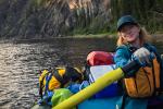 Woman pulling on oars in a boat on the water.