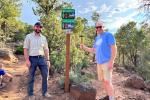 Outdoor Recreation Planners Mike Innes and Dave Jacobson stand in front of newly installed NRT sign.