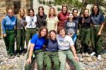 Female members of a fire crew encircle BLM Director standing outside next to a tree