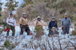 Five men in hard hats pose in a snowy forest