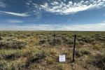 a fenced area is shown on a sagebrush and grass landscape with blue skies