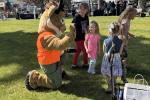 Seymour the Antelope kneels to greet children during Kemmerer Outdoor Discovery Day at Triangle Park with blue skies and green grass