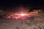 A smoldering bonfire next to some stacked pallets