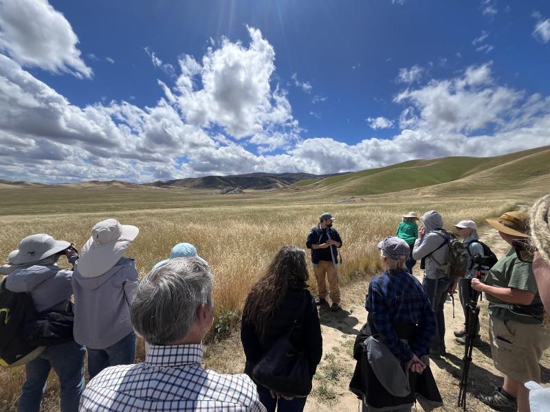 BLM archaeologist Dr. Zach Day leads a tour of Painted Rock on a blue sky day